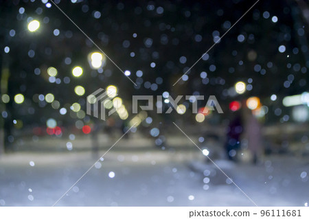 Blurred background. City view, lights, falling snow, night, street, bokeh spots of headlights of moving cars. Diffuse Urban backdrop winter scenery of street in city at night. Lantern light, snowfall Blurred background. City view, lights, falling snow, night, street, bokeh spots of headlights of moving cars. Diffuse Urban backdrop winter scenery of street in city at night. Lantern light, snowfall 96111681