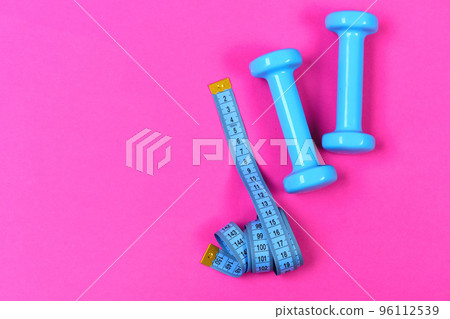 Barbells next to roll of tape measure. Health and sport 96112539