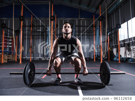 Athletic man works out at the gym with a barbell 96112658