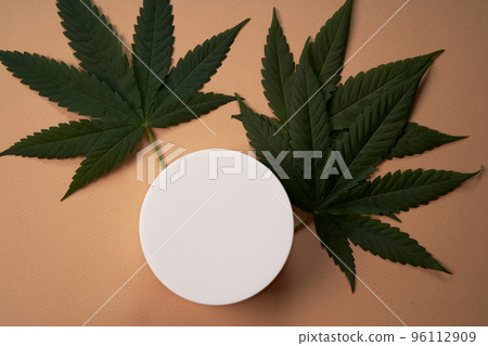 A mock-up for your face and body care cosmetic product based on medical cannabis. Cream on a light brown background. Copy space. Flat lay. Health and wellbeing concept. 96112909