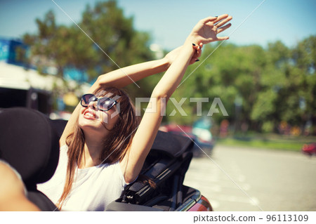 Young woman in cabriolet car departs for the summer holidays Young woman in cabriolet car departs for the summer holidays 96113109