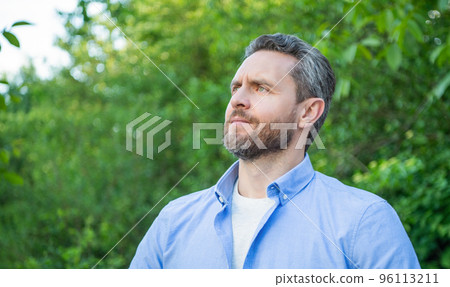 Portrait of handsome unshaven man looking aside natural background, copy space 96113211