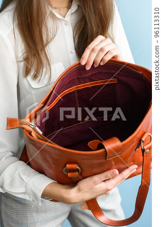 close-up photo of orange leather bag in a womans hands 96113310