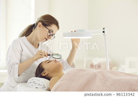 Beautician examine female patient face in saloon 96113342