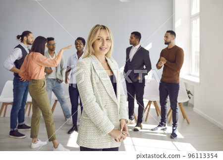 Portrait of beautiful and successful business woman standing against backdrop of workspace. Portrait of beautiful and successful business woman standing against backdrop of workspace. 96113354