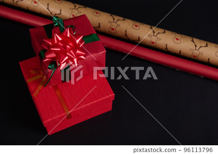 Still life with gift boxes, ornate with green ribbon and red tied bow, surrounded by wrapping paper on a black background. Copy space. Happy New Year. Merry Christmas. Winter holidays. Christmastime Still life with gift boxes, ornate with green ribbon and red tied bow, surrounded by wrapping paper on a black background. Copy space. Happy New Year. Merry Christmas. Winter holidays. Christmastime 96113796