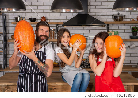 father mother and child in kitchen. family day. mom dad and daughter wear aprons. 96113899