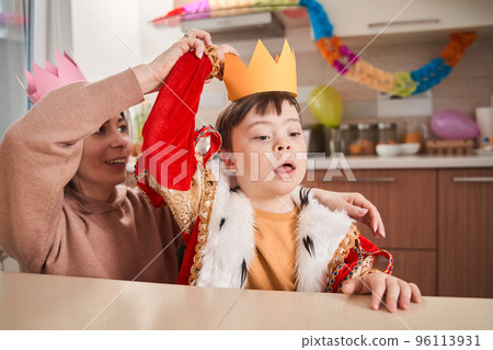 Little boy with genetic disorder wearing king costume preparing to the party with his mother Little boy with genetic disorder wearing king costume preparing to the party with his mother 96113931
