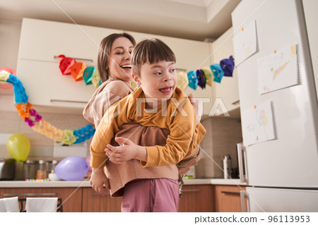 Mother playing with her son with genetic disorder at the kitchen 96113953