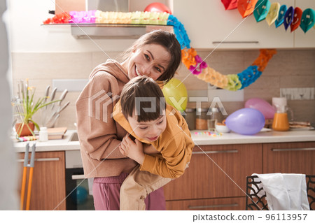 Young attractive mother playing with her son with genetic disorder at the kitchen Young attractive mother playing with her son with genetic disorder at the kitchen 96113957