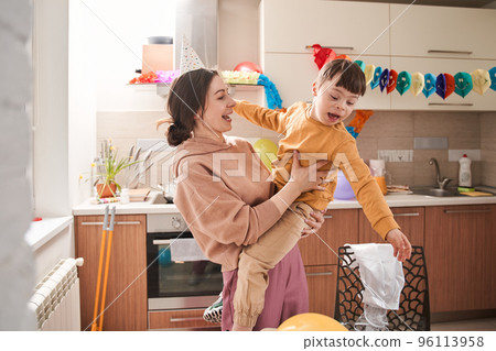 Little boy with Down syndrome joking and playing with his mother at the decorated kitchen 96113958