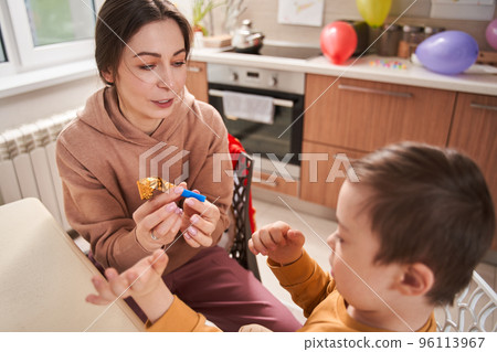 Caucasian woman holding party pipe and playing with her male child 96113967