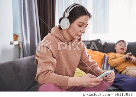 Lovely caucasian woman looking at the smartphone screen while sitting at the sofa 96113988
