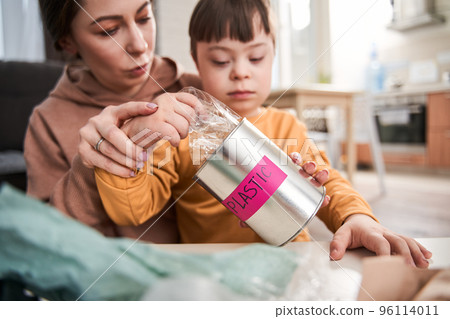 Family of mother and child boy with genetic disorder sorting garbage at home Family of mother and child boy with genetic disorder sorting garbage at home 96114011