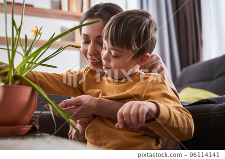 Boy with Down syndrome bonding to his lovely mother while she holding him at the hands Boy with Down syndrome bonding to his lovely mother while she holding him at the hands 96114141