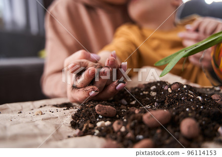 Mother teaching her little male child to replacing flowers to the pots at home Mother teaching her little male child to replacing flowers to the pots at home 96114153