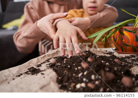 Boy stretching hands and looking with interest how his mother replacing flowers Boy stretching hands and looking with interest how his mother replacing flowers 96114155