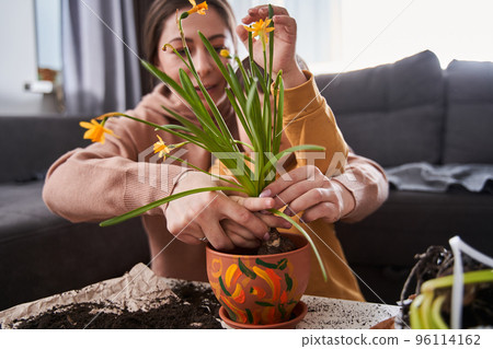 Boy with down syndrome looking with interest how his mother replacing flowers 96114162