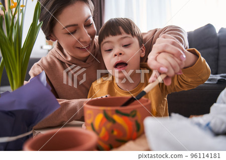 Friendly mother preparing soil for plants while spending time with her son Friendly mother preparing soil for plants while spending time with her son 96114181