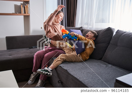 Woman and her child boy with genetic disorder playing with toy gun 96114185