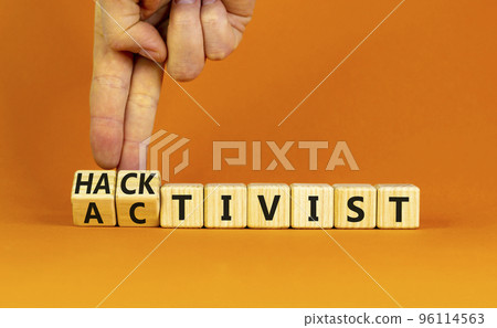 Activist or hacktivist symbol. Businessman turns wooden cubes and changes the word Activist to Hacktivist. Beautiful orange table orange background, copy space. Business activist or hacktivist Activist or hacktivist symbol. Businessman turns wooden cubes and changes the word Activist to Hacktivist. Beautiful orange table orange background, copy space. Business activist or hacktivist 96114563