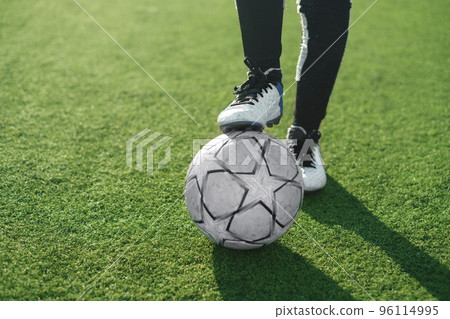 Close-up of a soccer ball and the feet of a football player in professional sports shoes. Youth soccer lessons at the stadium. 96114995