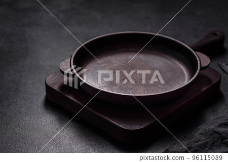 Brown iron empty pan with kitchen utensils on a dark concrete background 96115089