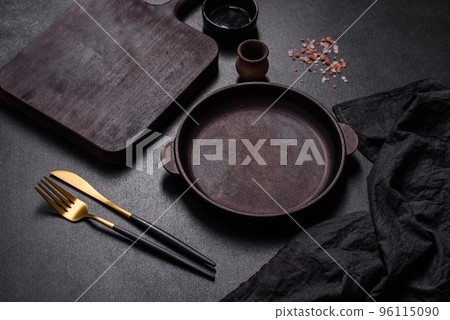 Brown iron empty pan with kitchen utensils on a dark concrete background 96115090
