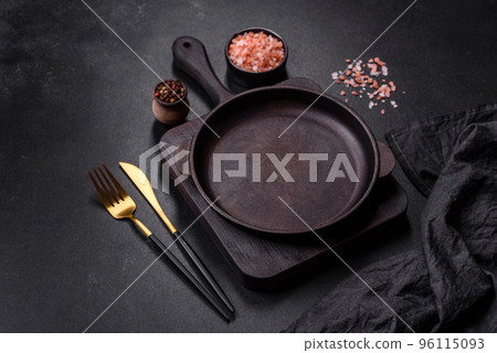 Brown iron empty pan with kitchen utensils on a dark concrete background 96115093