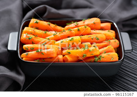 Roasted baby carrots in a ceramic form on a dark wooden table. Healthy root vegetables concept. Roasted baby carrots in a ceramic form on a dark wooden table. Healthy root vegetables concept. 96115167