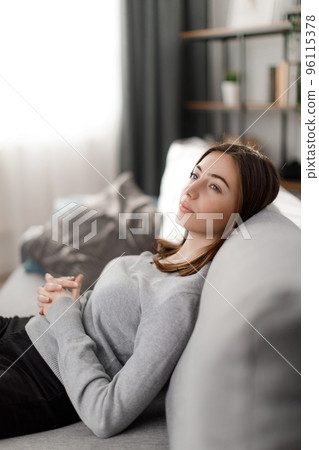 Dreamy woman resting on sofa 96115378