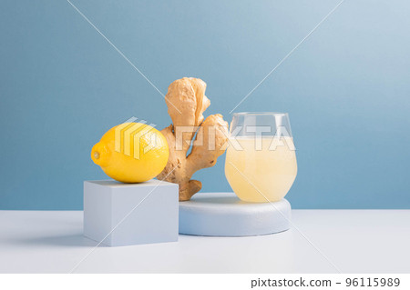 Antioxidant drink fresh ginger lemon in a glass trendy blue background, podium minimalism, balance Antioxidant drink fresh ginger lemon in a glass trendy blue background, podium minimalism, balance 96115989