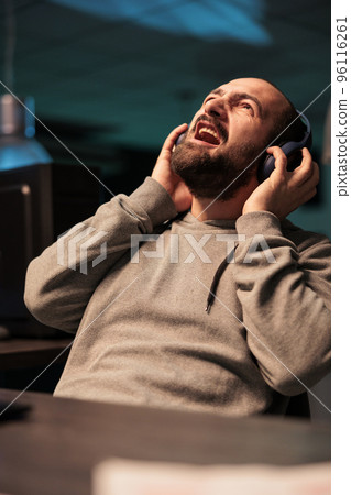 Silly young coder screaming and listening to music on headset, working on app developing software late at night. Web developer singing song in office, coding online cloud database. Silly young coder screaming and listening to music on headset, working on app developing software late at night. Web developer singing song in office, coding online cloud database. 96116261
