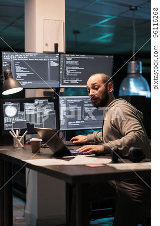 Software engineer writing code on multiple screens displaying artificial intelligence algorithm late at night. Programming online cloud computing on monitors to develop new html script. Software engineer writing code on multiple screens displaying artificial intelligence algorithm late at night. Programming online cloud computing on monitors to develop new html script. 96116268