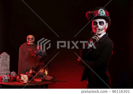 Santa muerte doing hush secret sign in studio, looking like goddess of death with skull make up and dios de los muertos costume. Showing slience privacy gesture celebrating mexican holiday. Santa muerte doing hush secret sign in studio, looking like goddess of death with skull make up and dios de los muertos costume. Showing slience privacy gesture celebrating mexican holiday. 96116301
