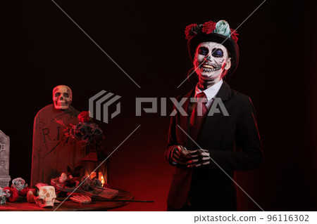 Happy smiling woman wearing santa muerte costume in studio, having skull make up with black and white. Celebrating day of the dead mexican halloween tradition, festival horror look. 96116302