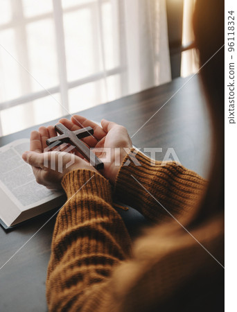 Woman sitting and studying the scriptures.The  wooden cross in the hands. Christian education concepts The Holy Scriptures open and pray 96118324