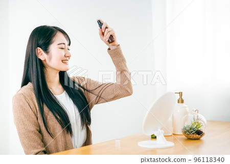 在頭髮上使用基本化妝品、噴霧和噴霧劑進行頭髮護理的女性 96118340