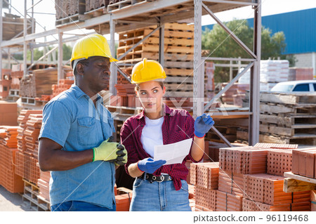 Couple of wokers checking order list at hardware store Couple of wokers checking order list at hardware store 96119468
