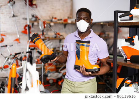 Man choosing boots in gardening tools store Man choosing boots in gardening tools store 96119616