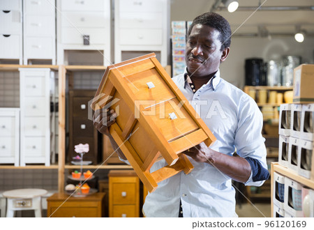 Portrait of man choosing chest of drawers in furniture store 96120169