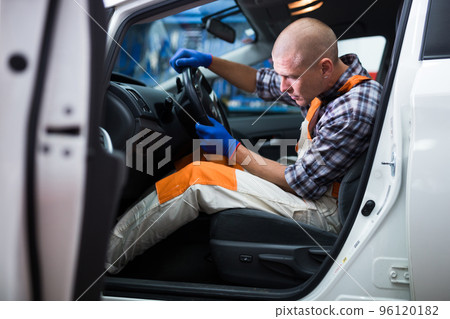 Auto mechanic sitting in broken car and listens to engine operation Auto mechanic sitting in broken car and listens to engine operation 96120182