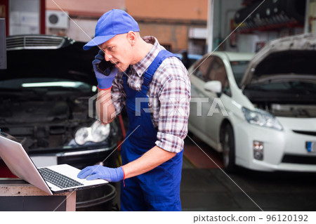 Car mechanic calls on smartphone to client Car mechanic calls on smartphone to client 96120192