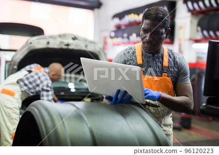 Mechanic using a laptop to work in service Mechanic using a laptop to work in service 96120223
