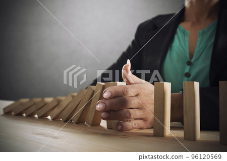 Businesswoman stops a chain fall like domino game. Concept of preventing crisis and failure in business 96120569