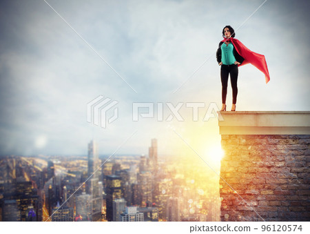 Successful businesswoman acts like a super hero above the roof of a building. Concept of determination and success Successful businesswoman acts like a super hero above the roof of a building. Concept of determination and success 96120574