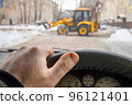 car driver hand on the steering wheel against the background of a tractor 96121401