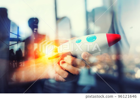 Businessman launches his startup company. Hand holding a wooden rocket. double exposure with light effects 96121646