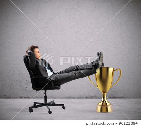 Winner businessman relaxing over a golden cup 96122884