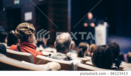 Speaker giving a talk in conference hall at business event. Rear view of unrecognizable people in audience at the conference hall. Business and entrepreneurship concept Speaker giving a talk in conference hall at business event. Rear view of unrecognizable people in audience at the conference hall. Business and entrepreneurship concept 96123413